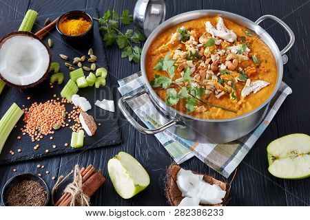 Hearty Spicy Mulligatawny Soup With Chicken Meat Sprinkled With Fried Cashew In A Metal Pot On A Bla