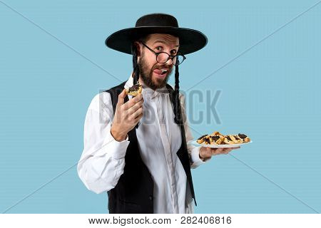 The Young Orthodox Jewish Man With Black Hat With Hamantaschen Cookies For Jewish Festival Of Purim 