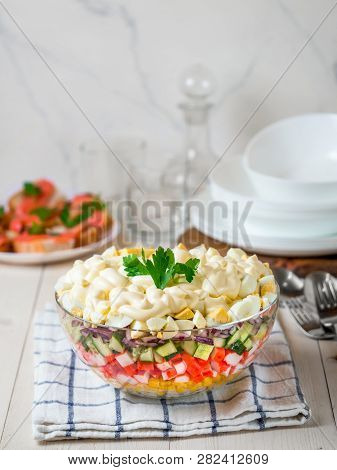 Large Glass Bowl With Crab Salad, Corn, Cucumber And Rice At Table. Layered Crab Sticks And Corn Sal