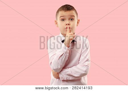 Secret, Gossip Concept. Teen Boy Whispering A Secret Behind His Hand. Child Isolated On Trendy Pink 