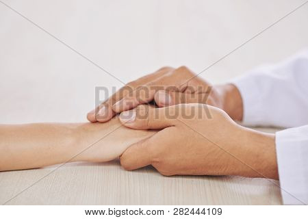 Hands Of Young Clinician In Whitecoat Holding Those Of His Patient While Supporting Her In Hospital