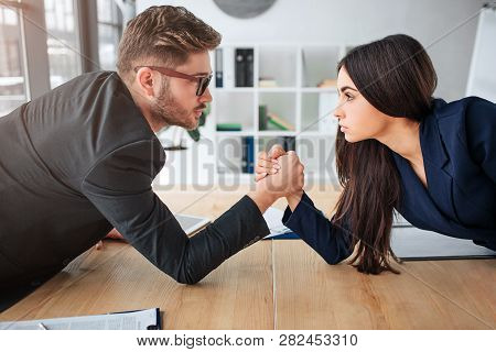 Young Man And Woman Have Competition. They Stand In Front Of Each Other And Look Serious. People Hol