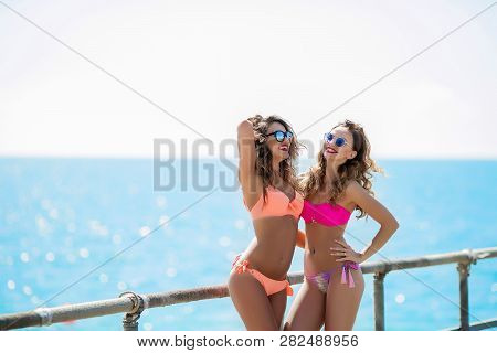 Sexual Girl In A Bright Bikini On A Sunny Beach. Bikini, Red Lips, Blue Sea, Tanned Girl. Two Friend