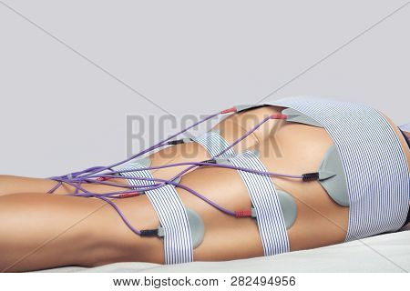 The Procedure Of Myostimulation On The Legs And Buttocks Of A Woman In A Beauty Salon. Caring For Th