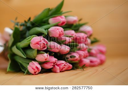Bouquet Of Bright Pink Tulips With A Beautiful Bow On A Wooden Background