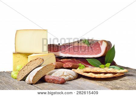 South Tyrolean Specialties Like Bacon, Sausages And Cheese Lying On A Rustic Table In Front Of A Whi