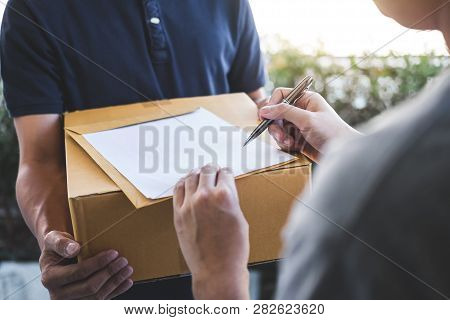 Delivery Mail Man Giving Parcel Box To Recipient, Young Man Signing Receipt Of Delivery Package From