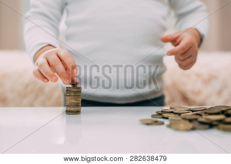 The Child Builds The Tower Of The Coins Closeup