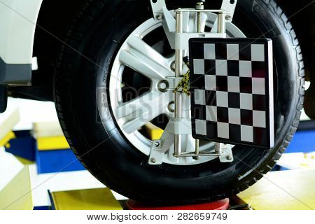 The Black And White Alignment Tool At The Metal Wheel Of White Car While Waiting On The Stop Positio