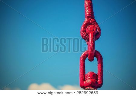 Links Of An Old Lifting Sling Of Red Color Closeup Against The Background Of The Sky