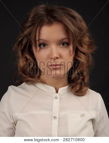 Young Woman In White Blouse With Curly Hair Looks Bewildered And Resented. Emotional Studio Portrait