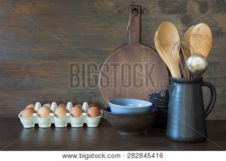 Crockery, Clayware, Dark Utensils And Other Different Stuff On Wooden Tabletop. Kitchen Still Life.