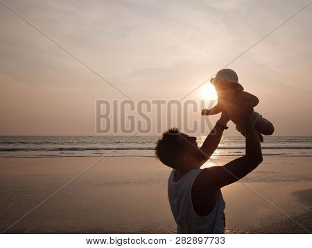 Dad Plays With His Laughing Baby Girl Opposite The Setting Sun