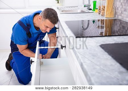 Close-up Of A Male Handyman Installing Door Of Drawer In The Kitchen