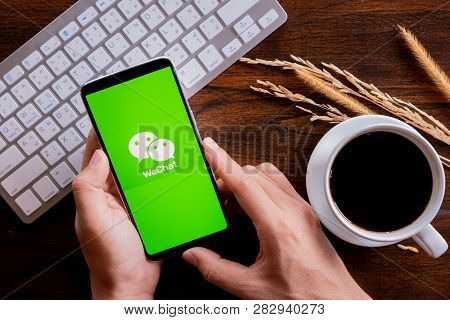Chiang Mai / Thailand - Jan 20 2019 : Hands Hoding Mobile With Wechat Screen, Coffee And Keyboard On