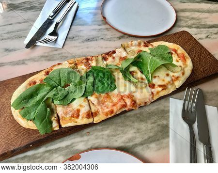 Pizzetta With Rocket Leaves , Arugula Or Rucola And Artichoke Slices On Wooden Pizza Board.