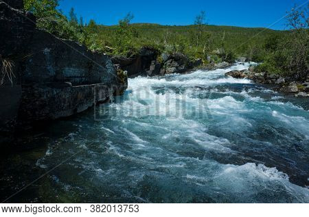 Nature of Scandinavia in summer. Clear water of Abiskojokk river in Abisko National Park in northern Sweden. Sunny day