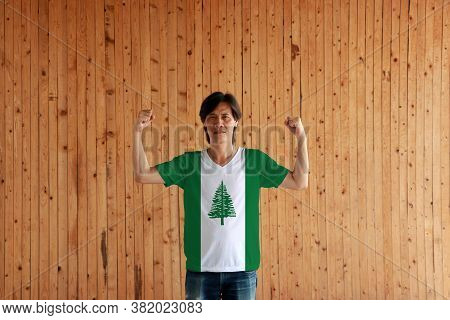 Man Wearing Norfolk Island Flag Color Of Shirt And Standing With Raised Both Fist On The Wooden Wall