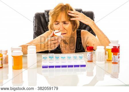 Senior Woman Confused About Medication To Add To Her Weekly Pill Dispenser