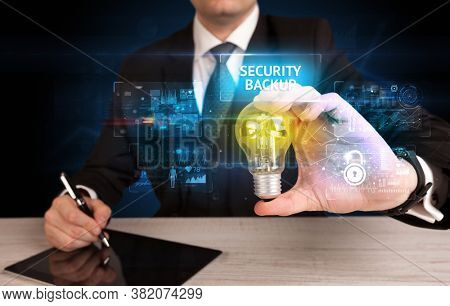 Businessman holding lightbulb with SECURITY BACKUP inscription, online security idea concept