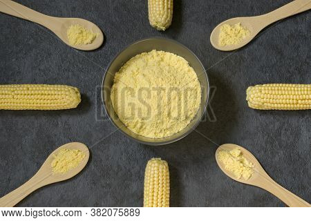 Fresh Corn On The Cob And Corn Grits In A Bowl And Wooden Spoons On A Dark Background. The Concept O