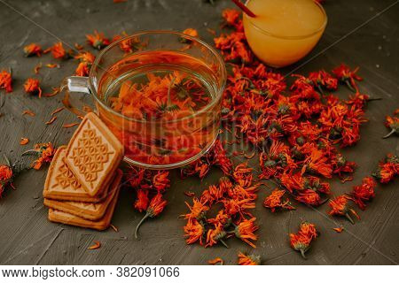Tea With Calendula Flowers And Biscuits. Transparent Glass Cup And Saucer