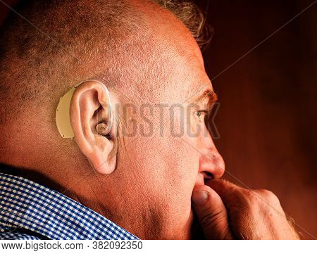 A Sad Old Man With A Hearing Aid In His Ear. Modern Hearing Aid For Deaf And Hard Of Hearing Patient
