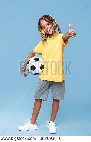 Full Lengh Image Of Cute Little Boy With African Dreads Holding Soccer Ball And Show Thumb Up Over B