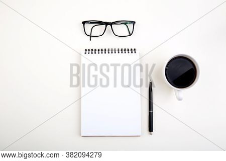 White Notepad With Black Pen And Glasses On Light Table, Top