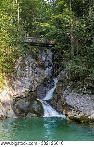Rindbach Waterfall With Wooden Bridge And Forest. Austria Alps Mountain