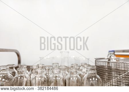 Empty Clear Glass Medicine Bottles Stand On A Cart. Medical Manufacturing Background