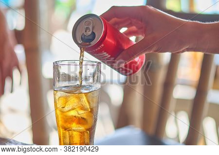 Boracay, Philippines - Jan 22, 2020: The Girls Hand Pours Coca-cola From A Metal Can Into A Glass Of