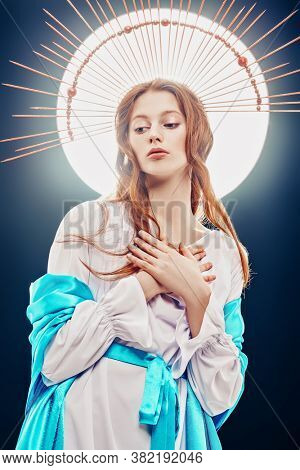 The Virgin Mary portrait on a dark background with rays of light. Modern art in religion. 