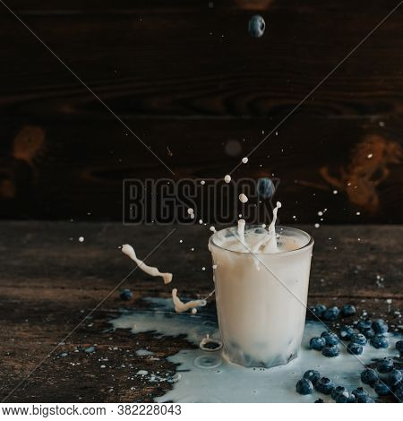 Berries Are Thrown Into The Transparent Glass Making Splashes Of Milk