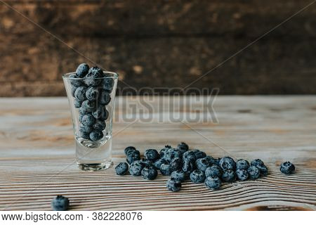 Fresh Blue Matte Round Blueberries Filled In A Transparent Glass And Scattered