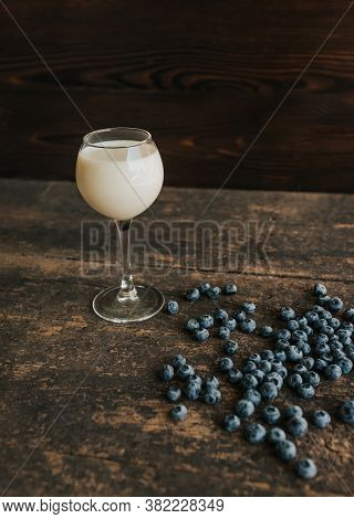 A Transparent Glass With Milk. Blue Fresh Blueberries Are Scattered
