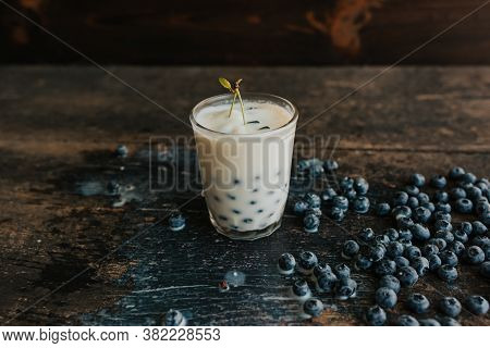 Blueberries Float In A Transparent Glass With Milk