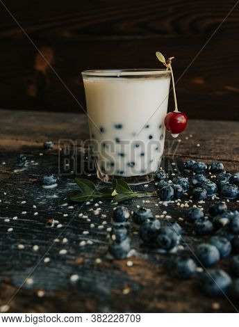 Blueberries Float In A Transparent Glass With Milk