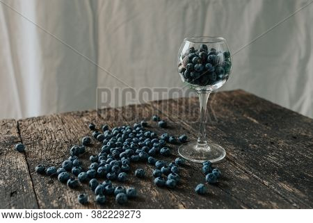 Blueberries Filled In A Transparent Glass And Scattered