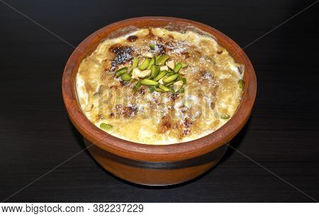 Traditional Arabic, Eastern Dessert Om Ali. Top View. Egyptian Bread Pudding In A Brown Bowl On Dark