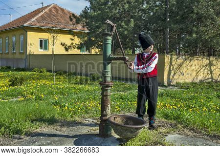 Ivanovo, Serbia, April 9, 2017. A Young Man Is Trying To Activate A Water Pump On The Street. The Bo
