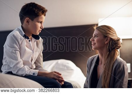 Eye Contact Between The Son And His Loving Mother, Sitting And Talking In The Bedroom.