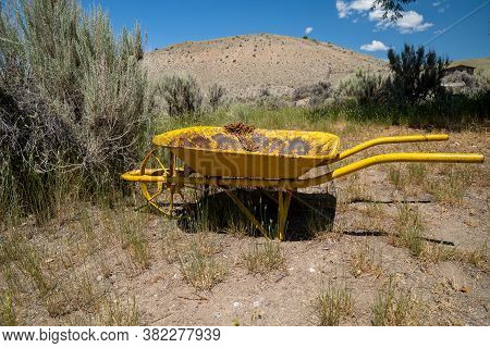 Old Yellow Rustic Rusted Wheelbarrow, Abandoned. Taken At Bannack Ghost Town In Montana