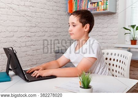 Teenager Boy Studying At Home Looking At Tutor At Laptop Screen During Quarantine Isolation Period. 