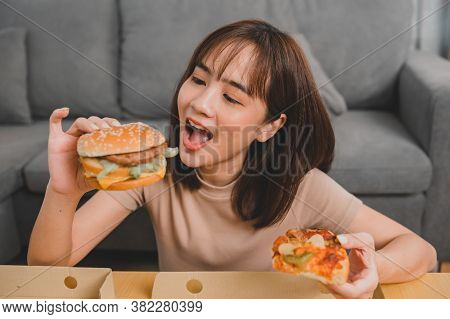 Fast Food Takeaway Back Home. Eating Burger When Takeout And Delivery. Asian Woman Lifestyle In Livi