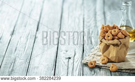 Traditional Italian Snack Taralli Or Tarallini In Paper Bag Over Old Gray Wooden Table. Rustic Shot 