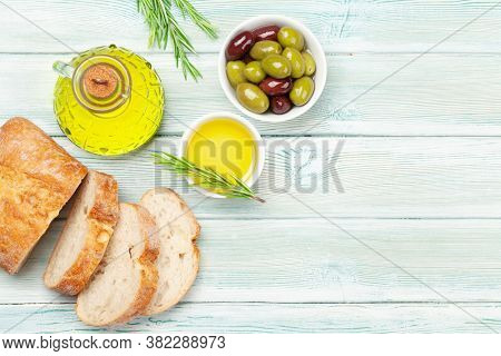 Ripe olives, olive oil and ciabatta bread. Top view flat lay with copy space
