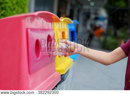 A Close Up Picture Of A Cute Young Asian Girl Throwing Away An Empty Plastic Water Bottle On A Recyc