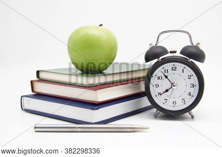 Back To School. Educational Concept, Office Supplies. A Stack Of Books, A Green Apple, An Alarm Cloc