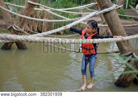A Cute Young Asian Girl With An Orange Life Vest Is Going Through An Obstacle Course At A Summer Cam